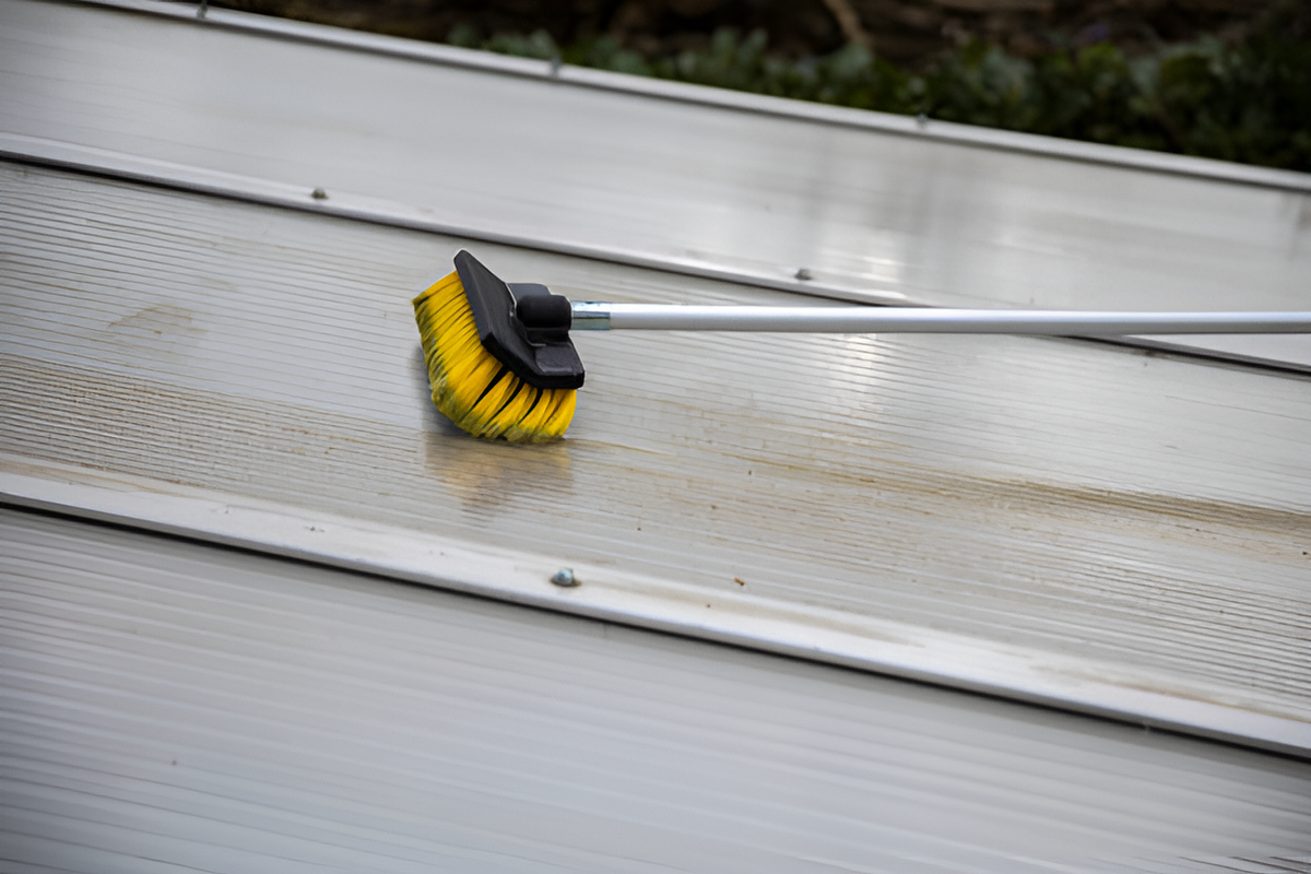 soft-bristled push broom on a metal roof